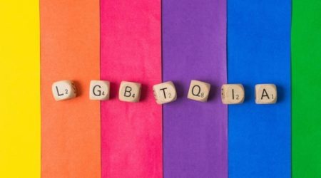 A imagem mostra letras sobre um fundo colorido e ilustra o artigo sobre Assistência Social e a população LGBTQIA+.