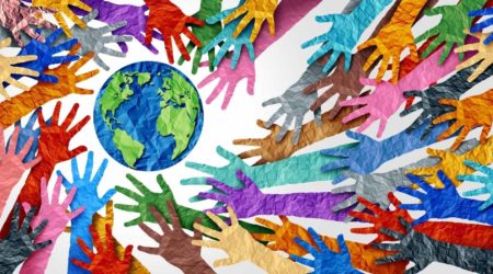 A imagem mostra mãos de papel coloridas indo em direção ao planeta Terra e ilustra o artigo sobre diversidade na escola.